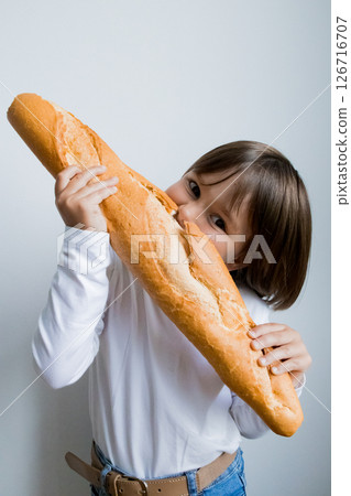 Young caucasian child enjoying large baguette packed with delight and curiosity 126716707