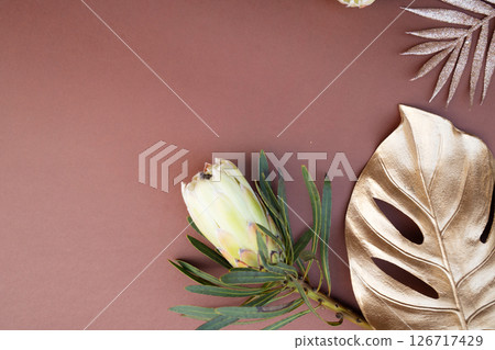 Tropical leaves and flowers over brown background, summer background with copy space Tropical leaves and flowers over brown background, summer background with copy space 126717429