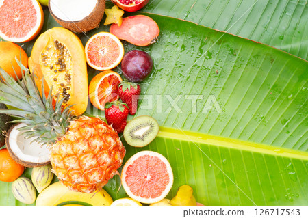 Summer mix of tropical fruits over green leaf Summer mix of tropical fruits over green leaf 126717543