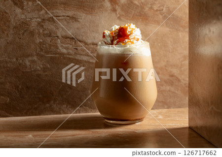 Iced caramel latte topped with whipped cream and caramel sauce. 126717662