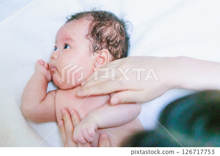 Mother applying lotion to her baby Mother applying lotion to her baby 126717753