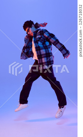 Dynamic photo of teen boy jumping of joy and happiness, full of playfulness and surprise in neon light against gradient background Dynamic photo of teen boy jumping of joy and happiness, full of playfulness and surprise in neon light against gradient background 126718032