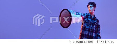 Banner. Boy holds megaphone stretched forward with serious expression, looking up with pride, in neon light against gradient background Banner. Boy holds megaphone stretched forward with serious expression, looking up with pride, in neon light against gradient background 126718049