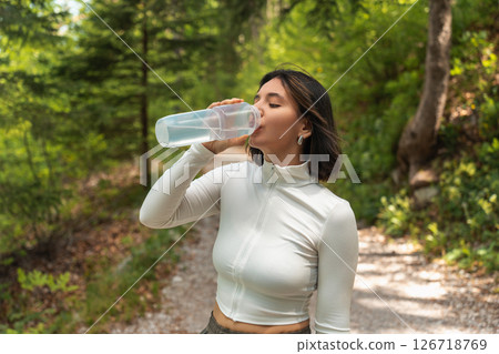 Pausing with purpose, a joyful hiker drinks water in forest shade, embracing summer warmth, balance, and outdoor simplicity Pausing with purpose, a joyful hiker drinks water in forest shade, embracing summer warmth, balance, and outdoor simplicity 126718769