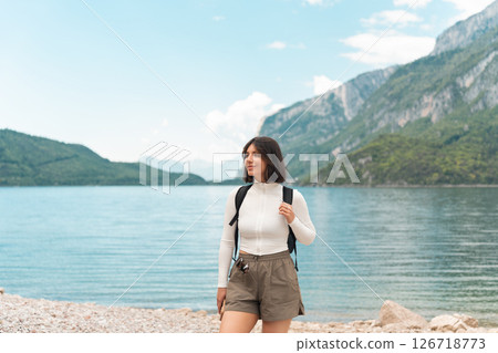 Lost in the moment, a happy woman hikes a quiet path between green hills, the lake glinting nearby and the mountains rising like a dream Lost in the moment, a happy woman hikes a quiet path between green hills, the lake glinting nearby and the mountains rising like a dream 126718773
