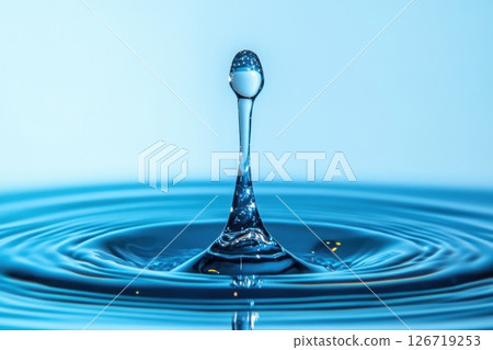 Close-up of a single water droplet captured mid-splash. Clear ripple effect on blue liquid surface. Minimalist style. Clean, pure, and refreshing concept. Studio lighting. Space for text. Banner. 126719253