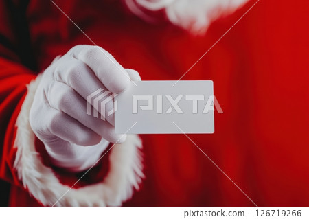 Close-up of Santa Claus hand in white glove holding blank card. Red festive suit and background. Christmas marketing concept. Space for text. Holiday theme. Mockup template. Copy space. Banner. Close-up of Santa Claus hand in white glove holding blank card. Red festive suit and background. Christmas marketing concept. Space for text. Holiday theme. Mockup template. Copy space. Banner. 126719266