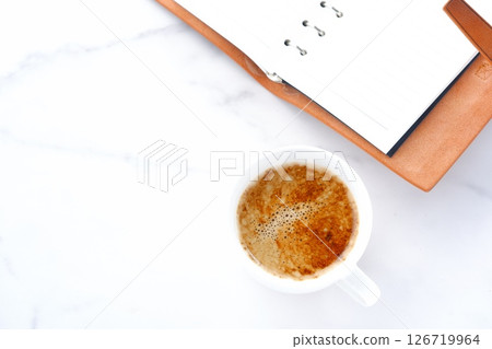 An image of someone writing in a diary while drinking a cafe latte, a coffee with plenty of milk. An image of someone writing in a diary while drinking a cafe latte, a coffee with plenty of milk. 126719964