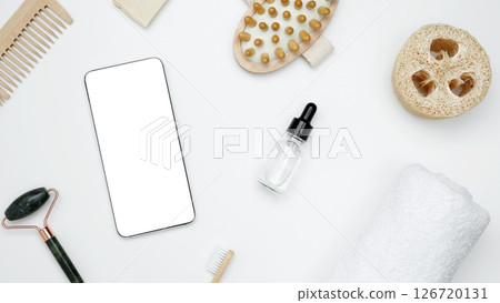 Smartphone with blank white screen surrounded by natural skincare and self-care products. Mockup for beauty and wellness design Smartphone with blank white screen surrounded by natural skincare and self-care products. Mockup for beauty and wellness design 126720131