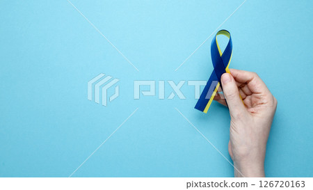 A person holds a yellow and blue awareness ribbon, symbolizing World Down Syndrome Day 126720163