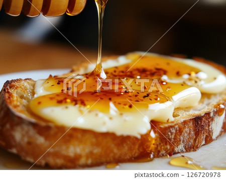Hot honey drizzle on a piece of fresh bread with cheese, demonstrating the versatility of this spicy-sweet condiment in casual meals 126720978