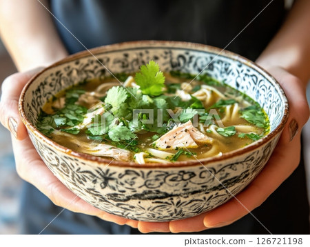 Traditional chicken noodle soup reimagined with fresh herbs and a creative twist, served in a vintage bowl 126721198