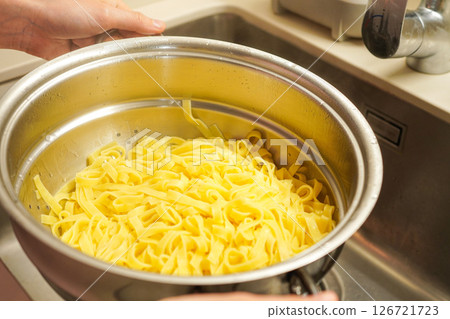 Cooked tagliatelle being drained in a colander Cooked tagliatelle being drained in a colander 126721723