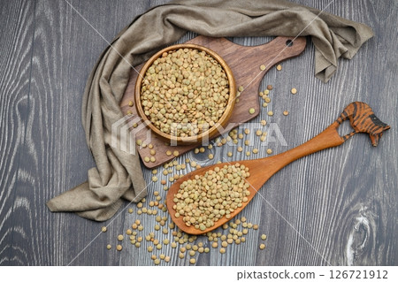 Green lentils in wooden bowl on wooden table background. Top view, copy space. Flat lay. Green lentils in wooden bowl on wooden table background. Top view, copy space. Flat lay. 126721912