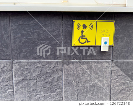 Accessible call button and Braille sign for wheelchair users on textured wall, symbolizing inclusive urban infrastructure and assistance for people with disabilities in public spaces Accessible call button and Braille sign for wheelchair users on textured wall, symbolizing inclusive urban infrastructure and assistance for people with disabilities in public spaces 126722348