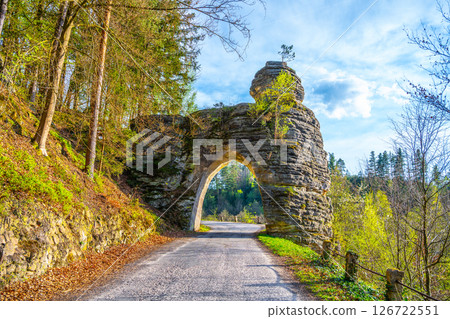 Pekar's Gate stands majestically in Bohemian Paradise, showcasing gothic sandstone architecture. Surrounded by lush trees, it marks a scenic pathway through the region's natural beauty. 126722551