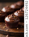 Delicious chocolate cupcakes sprinkled with crunchy nibs resting on wooden board 126724492