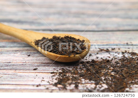 Dry black tea leaves isolated on wooden background, top view 126724750