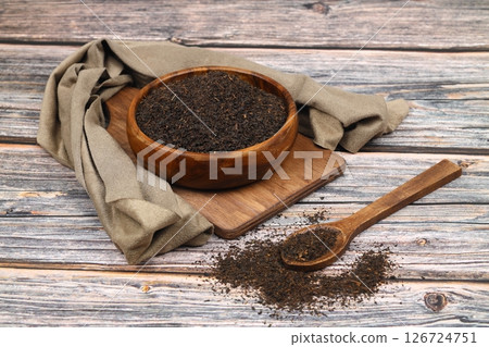 Dry black tea leaves isolated on wooden background, top view Dry black tea leaves isolated on wooden background, top view 126724751
