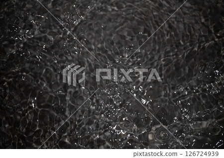 Black water with ripples. Defocus blurred black clear calm water surface texture with splashes and bubbles. Black water with ripples. Defocus blurred black clear calm water surface texture with splashes and bubbles. 126724939