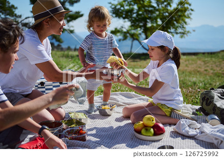 A family celebrating National Picnic Month by enjoying a delicious taco meal in nature on a sunny day, deepening familial bonds against a picturesque mountain backdrop. A family celebrating National Picnic Month by enjoying a delicious taco meal in nature on a sunny day, deepening familial bonds against a picturesque mountain backdrop. 126725992