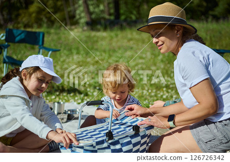 Mother Enjoying Quality Time with Her Children at a Family Picnic on a Sunny Day in Nature 126726342