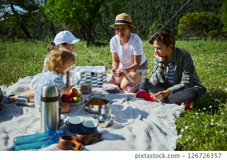 Family Enjoying a Picnic in the Mountains on a Sunny Summer Day 126726357