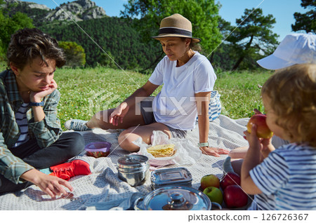 Mother Enjoying a Family Picnic in Scenic Mountain Nature on a Sunny Summer Day Mother Enjoying a Family Picnic in Scenic Mountain Nature on a Sunny Summer Day 126726367
