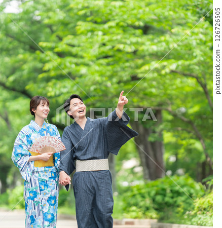 A couple in yukata walking along a tree-lined street 126726505
