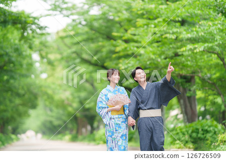 A couple in yukata walking along a tree-lined street A couple in yukata walking along a tree-lined street 126726509