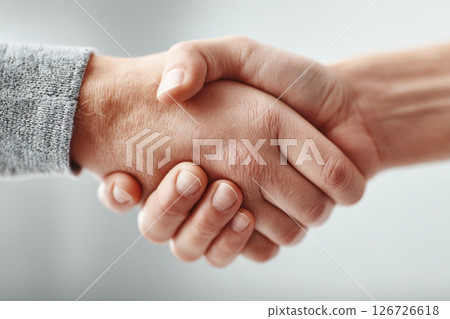 Two hands meet in a firm handshake symbolizing trust and agreement in a professional setting. 126726618