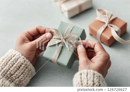 A person carefully holds a beautifully wrapped gift box showcasing a moment of anticipation and care. 126726627