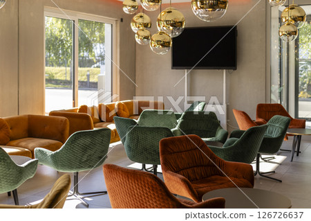 Bright lounge area with an array of colorful chairs and pendant lights. The spacious design invites relaxation and conversation, making it an ideal spot for social gatherings 126726637