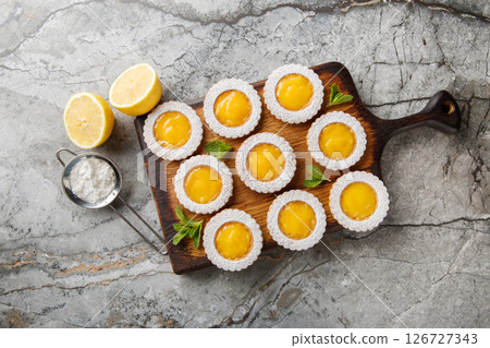 Homemade lemon curd shortbread cookies in the shape of a flower sprinkled with powdered sugar closeup on wooden board. Horizontal top view Homemade lemon curd shortbread cookies in the shape of a flower sprinkled with powdered sugar closeup on wooden board. Horizontal top view 126727343