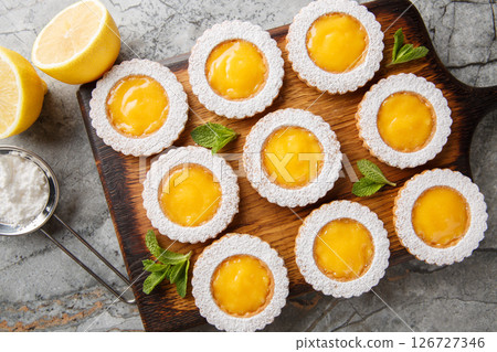 Lemon Curd Cookies feature a soft and buttery lemon cookie filled with a bright citrusy homemade lemon curd closeup on wooden board. Horizontal top view 126727346