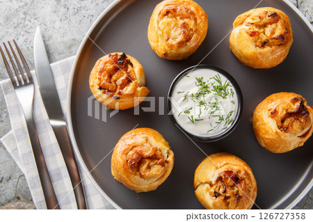 Ukrainian Knysh are pies with onion and potato filling served with sour cream close-up in a plate. Horizontal top view Ukrainian Knysh are pies with onion and potato filling served with sour cream close-up in a plate. Horizontal top view 126727358