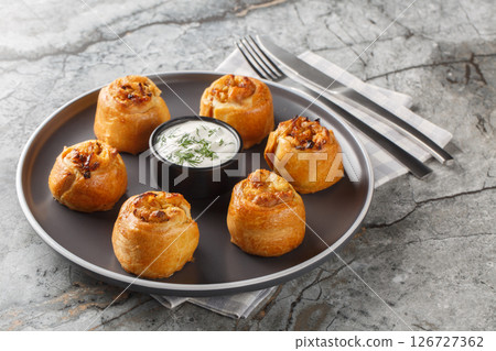 Baked Knysh pies with onion potato filling served with sour cream close-up in a plate. Horizontal Baked Knysh pies with onion potato filling served with sour cream close-up in a plate. Horizontal 126727362