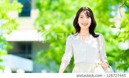 Smiling female businesswoman walking outdoors in summer 126727445
