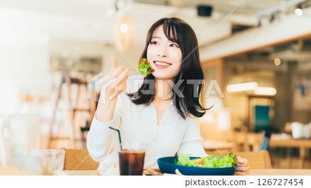Smiling woman/businesswoman eating lunch at a cafe Smiling woman/businesswoman eating lunch at a cafe 126727454
