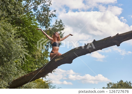 Girl sitting high up on a fallen tree 126727676