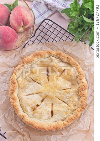 Freshly baked old fashioned deep dish peach pie cooling on baking rack, vertical top view 126727793