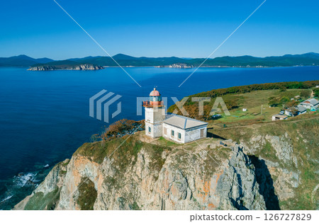 Beautiful coastal lighthouse standing atop a cliff overlooking the ocean during a clear sunny day 126727829