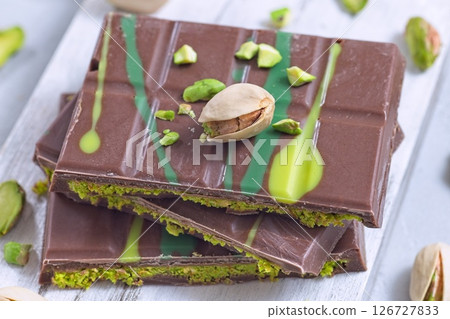 Dubai style milk chocolate bar with pistachio and kadaifi filing, lying on cutting board, horizontal 126727833