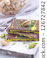 Dubai style milk chocolate bar with pistachio and kadaifi filing, lying on cutting board, vertical 126727842