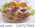 Grilled chicken legs and breast with lemon and lettuce on wooden board, horizontal 126727844