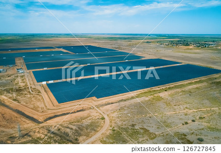 Solar energy farm located in a vast arid landscape generating renewable energy under clear blue skies Solar energy farm located in a vast arid landscape generating renewable energy under clear blue skies 126727845