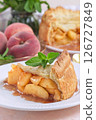 Delicious peach pie slice garnished with fresh mint, on white plate, vertical 126727849