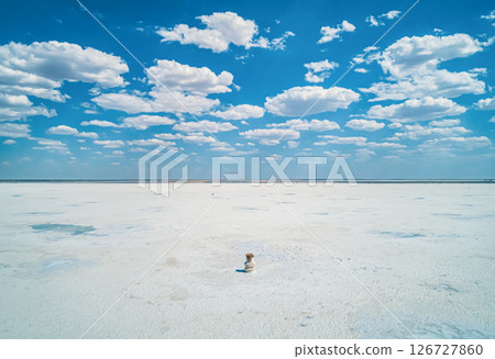Baskunchak Lake reveals its vast salt flats glistening under the sun, surrounded by a blue sky dotted with white clouds. Baskunchak Lake reveals its vast salt flats glistening under the sun, surrounded by a blue sky dotted with white clouds. 126727860