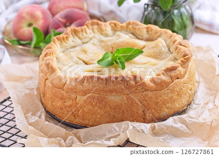 Freshly baked old fashioned deep dish peach pie cooling on baking rack, horizontal 126727861