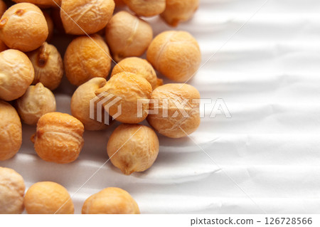 Raw chickpeas on packaging white ribbed paper. Uncooked grocery ingredient. Macro shot. Raw chickpeas on packaging white ribbed paper. Uncooked grocery ingredient. Macro shot. 126728566